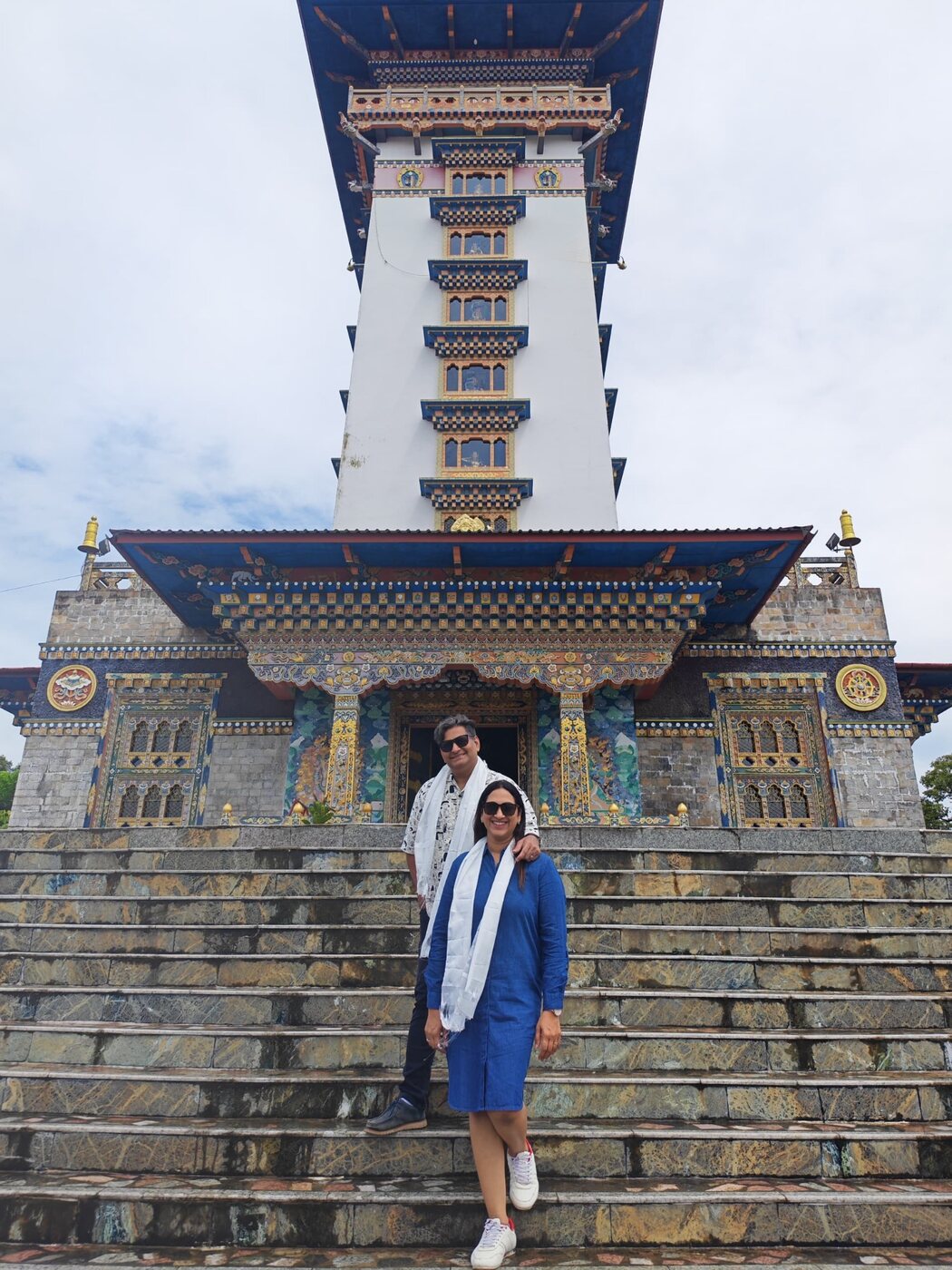 Travellers wearing ceremonial white scarves on the steps of an ornate Bhutanese temple