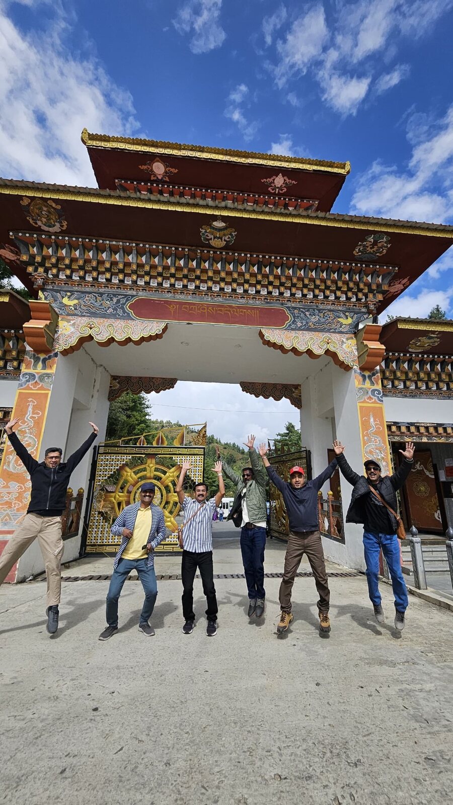 A group of travellers jumping beneath an ornate traditional gateway in Thimphu, Bhutan